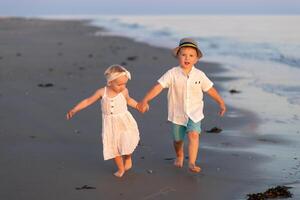 Children play joyfully on the beach, holding hands during sunset at a peaceful shoreline photo