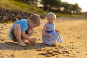 Boy and girl playing on the beach, digging in the sand photo