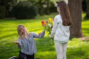 Daughter gifting mother tulips. Family celebration, love and appreciation. photo