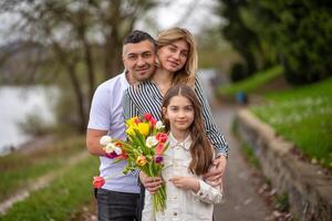 Family of three, man, woman and girl with tulips enjoying spring photo