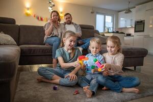 children brother and sisters have fun playing on the floor at home while parents are relaxing on the sofa photo