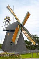 Historic windmill with bright sails turning in the breeze surrounded by lush greenery in a quiet village photo