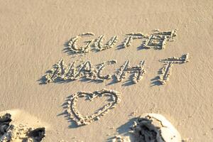 Good night message written in the sand on a beach during sunset, with gentle waves lapping at the shore, creating a peaceful atmosphere photo