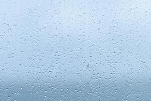 Raindrops forming a delicate pattern on a window pane, blurring the outside view during a cloudy afternoon in early fall photo
