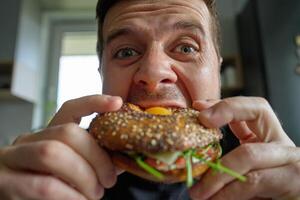 Close-up of hungry man eating breakfast sandwich, biting bagel with egg photo