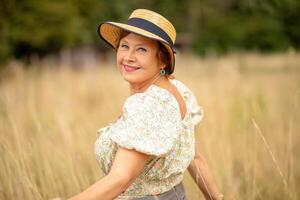 Woman in a straw hat enjoying a sunny day in a field of golden grass photo
