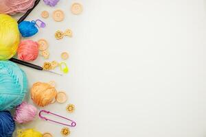 Flat lay composition with knitting threads and hook and buttons on white table, space for text, top view photo