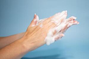 Woman washing hands with soap on color background photo