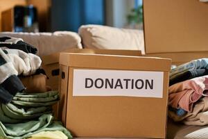 Clothes prepared for donation in cardboard box at home photo
