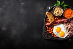 English breakfast on a plate with scrambled eggs, sausages, bacon, beans, toast and coffee on a dark stone background. photo