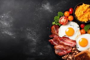 English breakfast on a plate with scrambled eggs, sausages, bacon, beans, toast and coffee on a dark stone background. photo