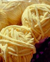 High-resolution closeup of soft yellow chenille yarn balls. The thick, fluffy texture is ideal for knitting, crochet, and creative DIY projects. Warm light enhances the cozy surface. photo