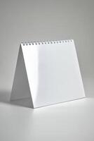 Blank tabletop calendar standing upright showcasing a minimalistic design against a neutral background photo