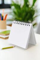 Sketchbook and pencil resting on a table among stationary items in a bright workspace photo