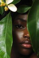 Woman's face partially hidden behind lush green leaves in a close-up portrait showcasing natural beauty and serene expression photo