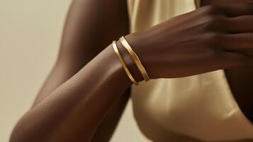 Elegant gold bracelets shine on a model's wrist against a neutral background photo