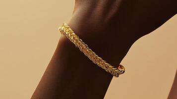 Elegant gold bracelet displayed on a smooth dark-skinned wrist with a soft beige background highlighting its intricate design photo