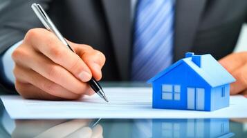 Signing a real estate contract with a miniature house on the table and a pen in hand during a business meeting photo