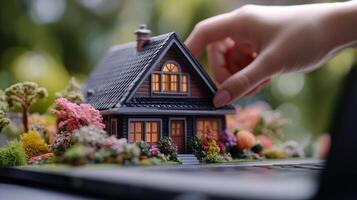 Miniature home model being adjusted in a serene garden setting during daylight hours photo