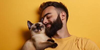 Man enjoys a joyful moment with his playful cat against a vibrant yellow backdrop in a cozy indoor setting photo
