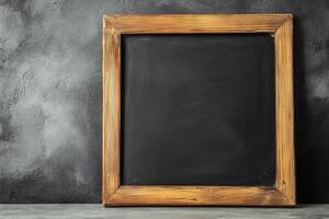 Blank chalkboard with wooden frame against a dark gray wall perfect for a creative display or informative messages photo