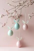 Pastel colored easter eggs with bunny ears create a playful springtime display against a soft pink backdrop photo
