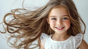 Bright smile of a young girl with flowing hair captures joy and innocence in a soft indoor setting photo