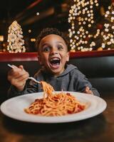 Excited child enjoys a large plate of spaghetti in a cozy restaurant with festive decorations photo