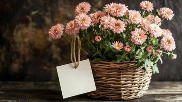 Beautiful pink flowers in a woven basket with a blank tag on a rustic wooden table photo