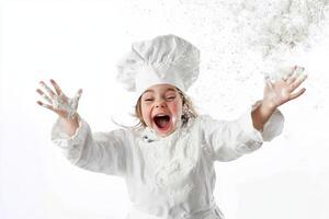 Young chef joyfully throws flour in the air while wearing a chef hat and coat in a bright kitchen setting photo