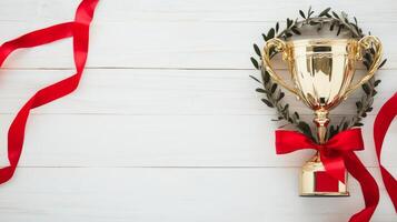 Golden trophy adorned with a laurel wreath and red ribbon on a wooden background celebrating achievement and success in competitions and awards ceremony concept photo