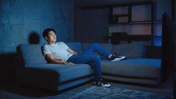 Young man relaxing on a sofa in a dimly lit living room during evening hours photo