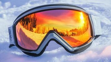 Reflective ski goggles resting on the snow at sunset in a mountain landscape photo