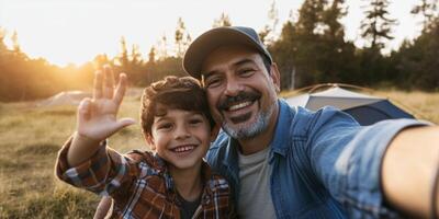 Father and son joyfully take a selfie while camping in nature during sunset, capturing a moment of happiness photo