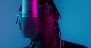 A man with dreadlocks and glasses is in front of a microphone photo