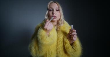 A woman in a yellow fur coat holding a cigarette photo