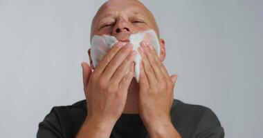 A bald man shaving his face with a razor photo