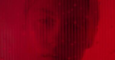 A man is looking into the camera through a red background photo