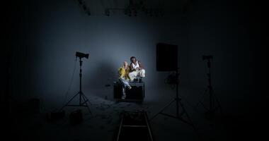 Two people sitting in a dark room with lights photo