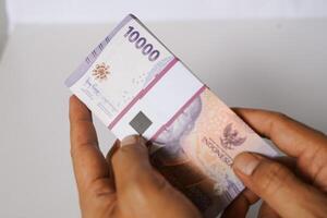 Handling a stack of ten thousand Indonesian Rupiah notes currency photo