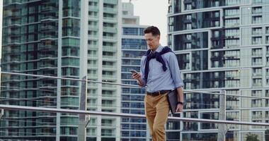 A man in a tie and pants standing on a bridge with a cell phone photo