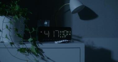A clock is shown on a table in the dark photo