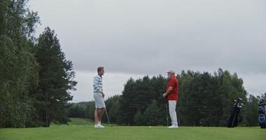 Two stylishly dressed men with a great age gap chat and play golf together photo