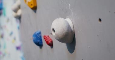 Man climbs the climbing wall, grabbing the artificial ledges imitating stones photo