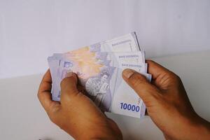 Close-up on hands holding Indonesian Rupiah currency, 10000 IDR banknotes photo