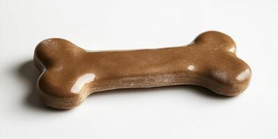 Dog treat shaped like a bone resting on a white surface in natural light during the day photo
