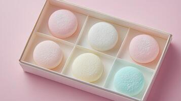 Delicate pastel desserts in a box arranged with care on a soft pink background photo