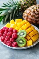 Fresh tropical fruit platter with pineapple, mango, kiwi, and raspberries ready for a summer gathering photo