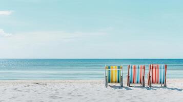 Colorful beach chairs arranged on sandy shore with gentle waves in the background during bright daylight photo