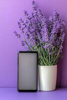 Lavender plant beside a smartphone against a purple background in a cozy indoor setting photo